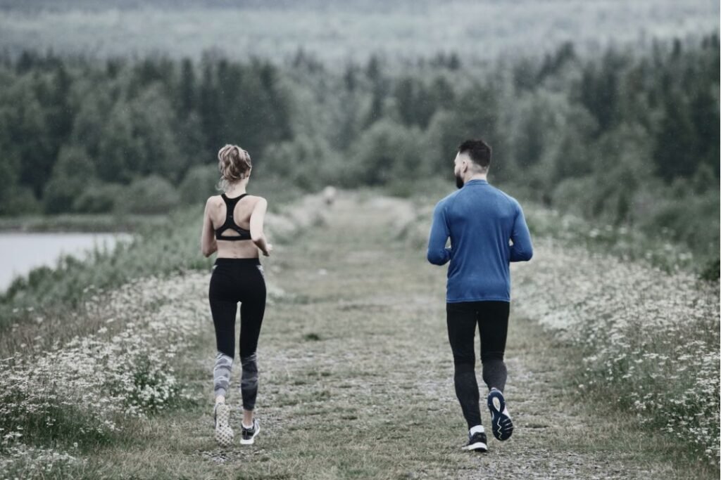 Un coach et sa cliente font de la course à pied dans la nature.