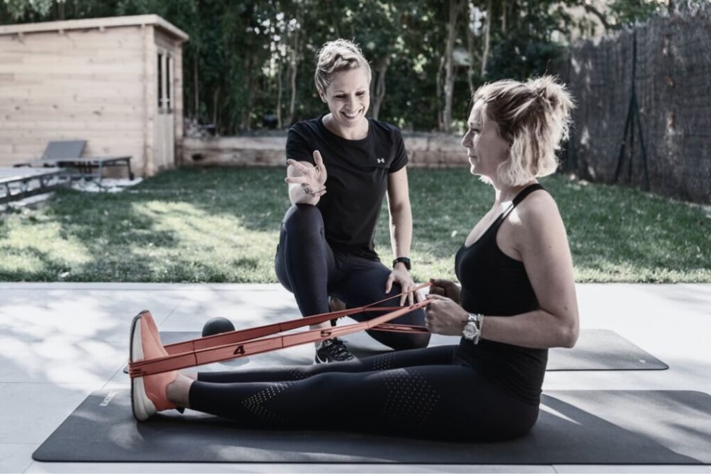 Une coach sportif Domicil'Gym spécialisée pour les femmes fait réaliser un exercice à sa cliente.