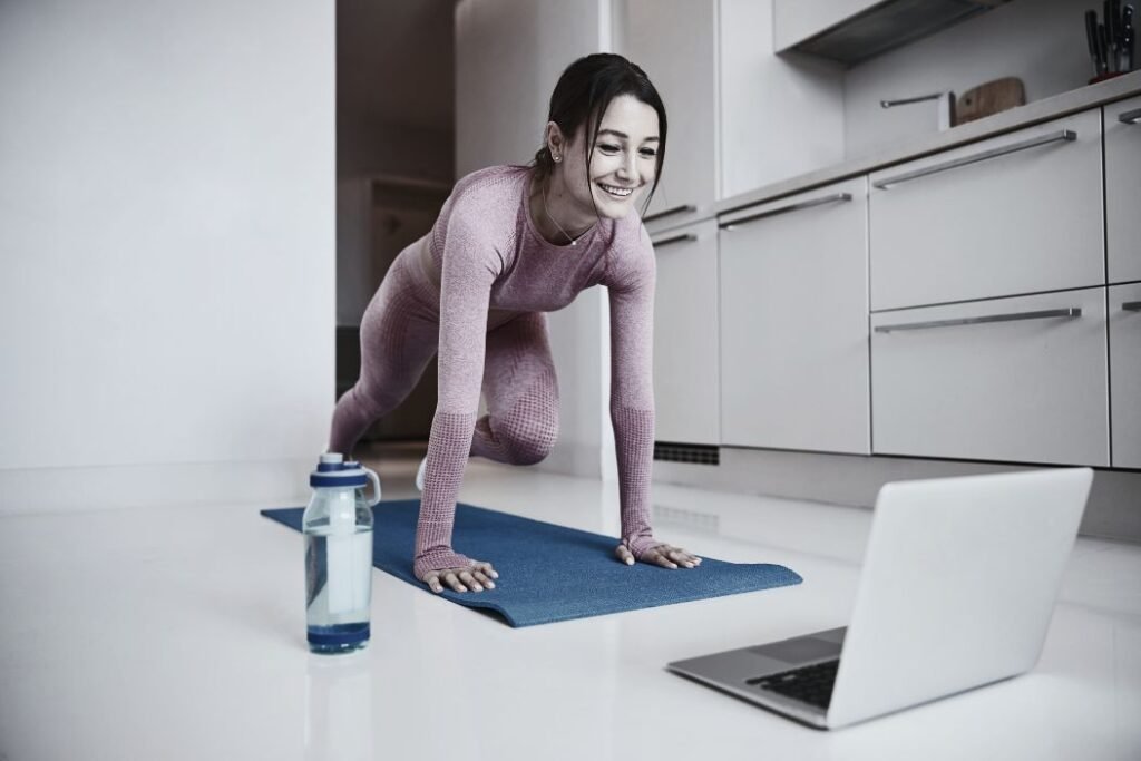 Une sportive fait du gainage en regardant sa tablette pour perdre du poids.