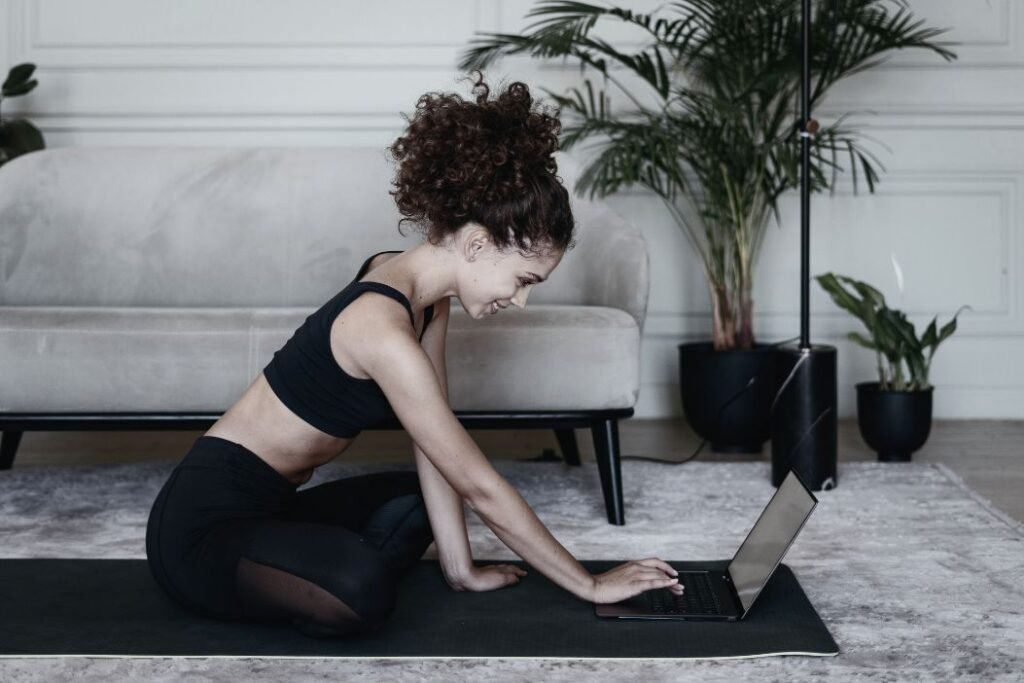 Une femme dans son salon suit un cours de sport en ligne.