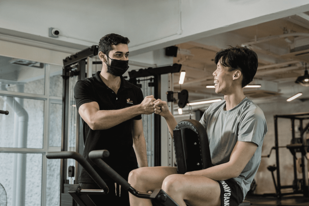 Un coach sportif conseille son client en salle de musculation.