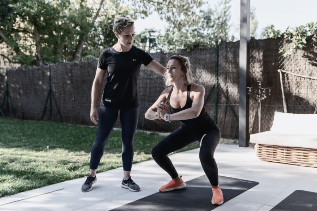 La cliente exécute un squat sous la supervision de sa coach sportive.